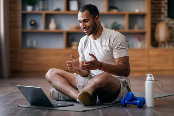 A person seated on a mat using a laptop in a wellness learning setting